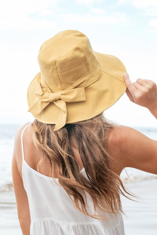 Woman wearing a wide-brimmed Bow Accent Cargo Hat at the beach.