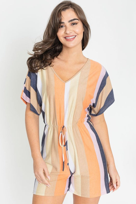 Dressed in the Summer Stripe Surplice Romper, featuring vertical stripes in green, beige, and pink, one highlights its handcrafted elegance. Made in the United States, it makes a striking impression against a plain white backdrop.