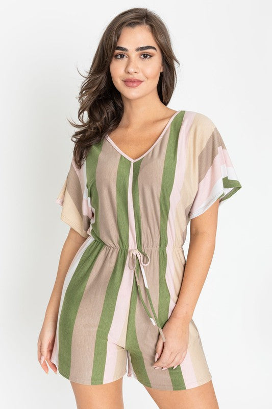 Dressed in the Summer Stripe Surplice Romper, featuring vertical stripes in green, beige, and pink, one highlights its handcrafted elegance. Made in the United States, it makes a striking impression against a plain white backdrop.