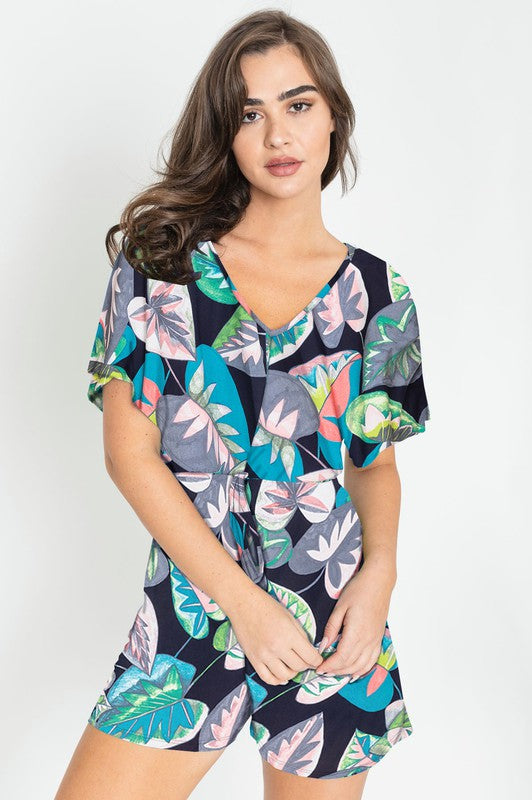 A person wearing a Plus Tropical Kimono Sleeve Romper is smiling, standing against a neutral background.