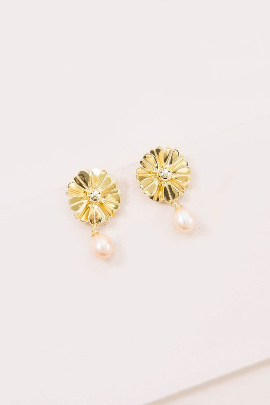 Flora Drop Earrings in 14k gold plating showcase delicate golden petal motifs with sophisticated pearl drop pendants, set against a light background.