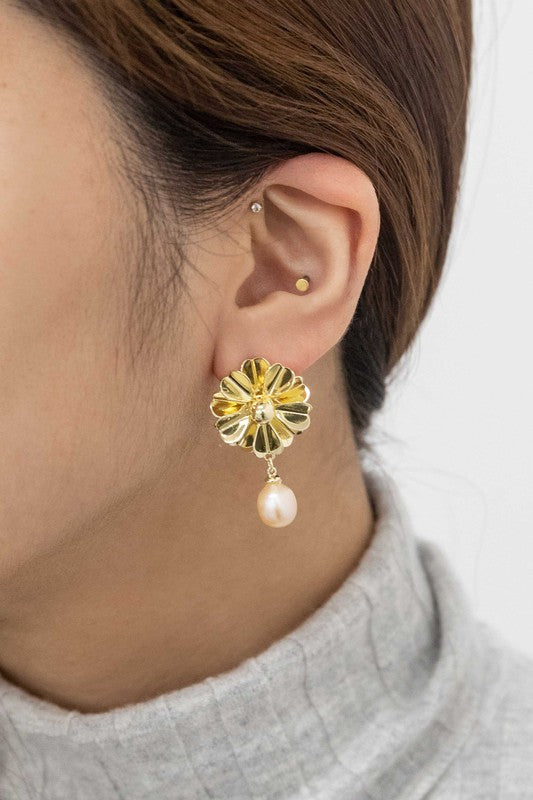 Flora Drop Earrings in 14k gold plating showcase delicate golden petal motifs with sophisticated pearl drop pendants, set against a light background.