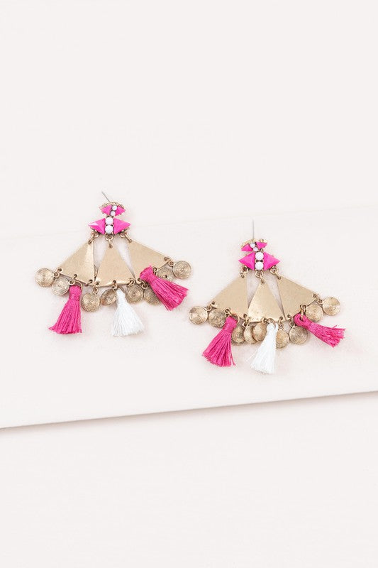 The Leinani Tassel Earrings feature gold triangles, pink and white tassels, and are adorned with small round charms in a bohemian style.