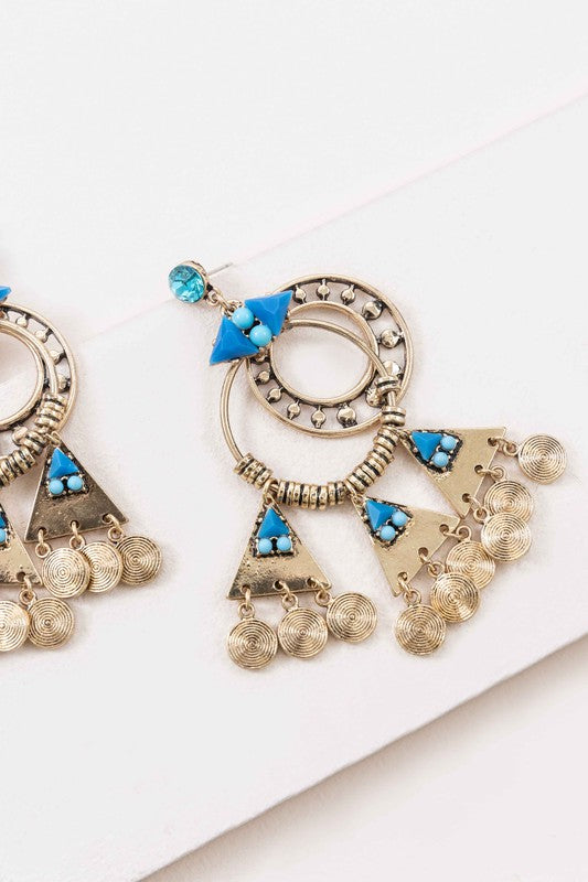 Olani Earrings showcase a bohemian style with silver and blue tones, featuring circular and triangular designs adorned with turquoise stones and hanging coin-like ornaments.