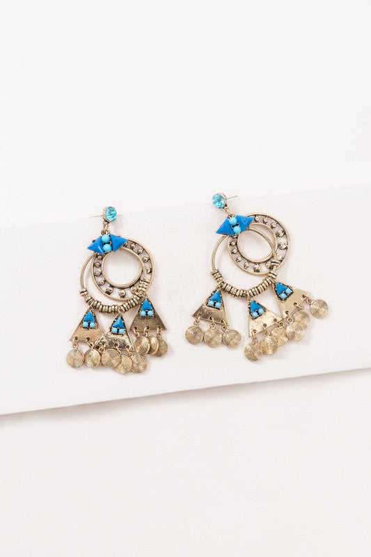 Olani Earrings showcase a bohemian style with silver and blue tones, featuring circular and triangular designs adorned with turquoise stones and hanging coin-like ornaments.