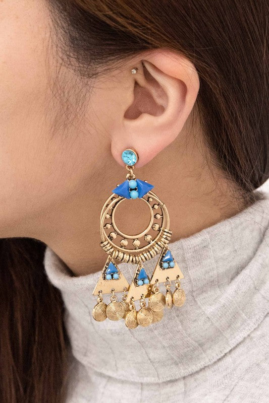 Olani Earrings showcase a bohemian style with silver and blue tones, featuring circular and triangular designs adorned with turquoise stones and hanging coin-like ornaments.