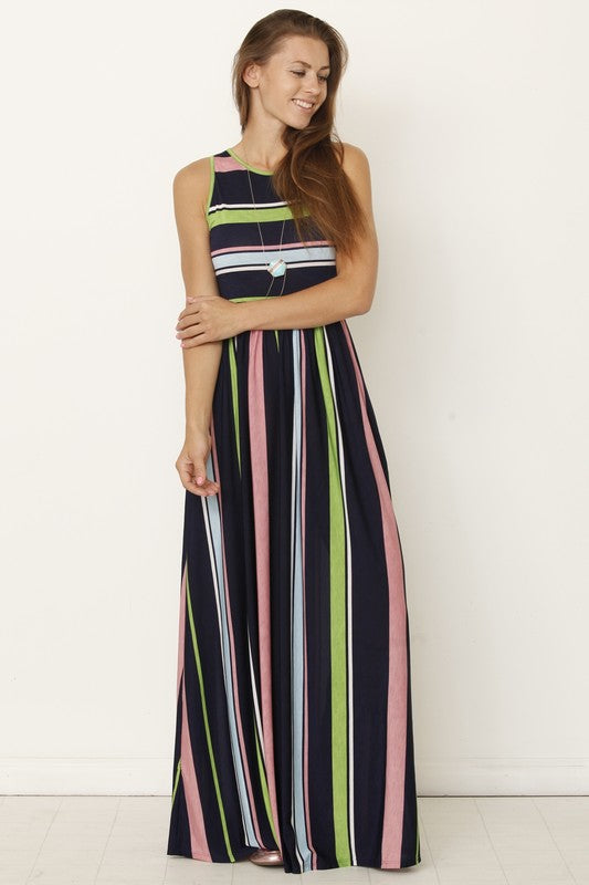 A person wearing the Multi Stripe Rainbow Maxi Dress stands against a plain background, hands in pockets and smiling.