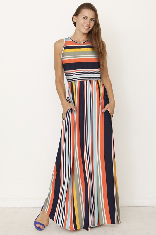 A person wearing the Multi Stripe Rainbow Maxi Dress stands against a plain background, hands in pockets and smiling.