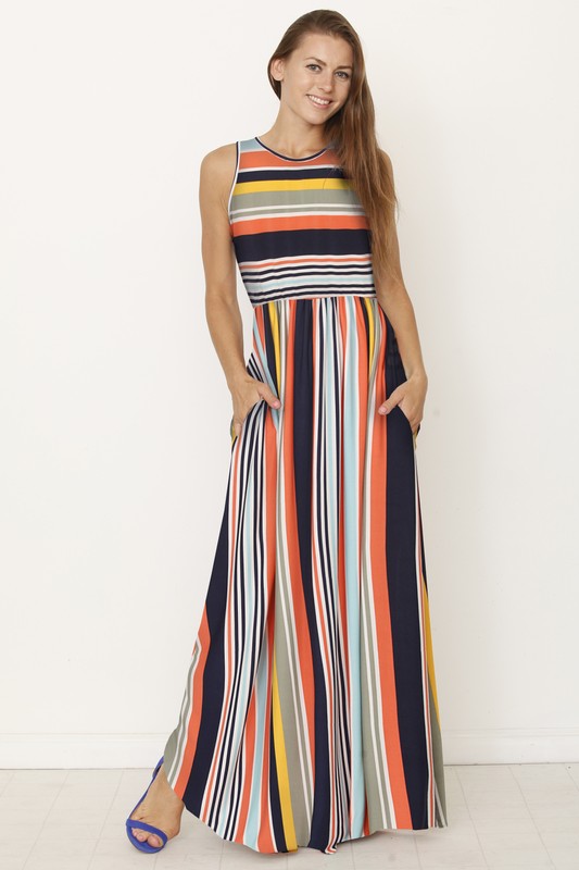 Someone is standing against a light-colored backdrop, wearing the Multi Stripe Rainbow Maxi Dress, a sleeveless garment featuring vertical stripes in shades of blue, green, pink, and purple.