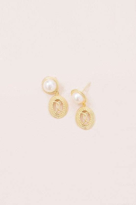 The Reminiscent Drop Earrings, featuring pearl studs and round, textured pendants, shine elegantly against a light background. Perfect as bridal jewelry, these exquisite pieces are 14k gold plated and exude classic charm for any special occasion.