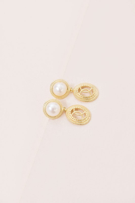 The Reminiscent Drop Earrings, featuring pearl studs and round, textured pendants, shine elegantly against a light background. Perfect as bridal jewelry, these exquisite pieces are 14k gold plated and exude classic charm for any special occasion.