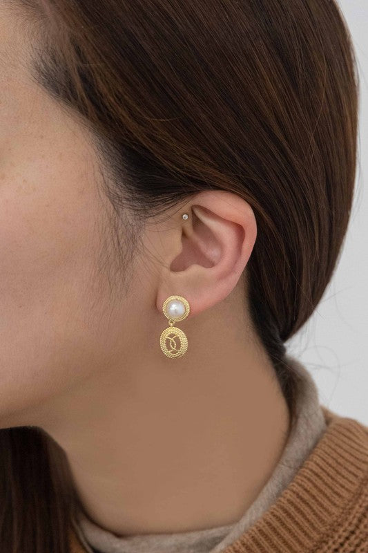 The Reminiscent Drop Earrings, featuring pearl studs and round, textured pendants, shine elegantly against a light background. Perfect as bridal jewelry, these exquisite pieces are 14k gold plated and exude classic charm for any special occasion.