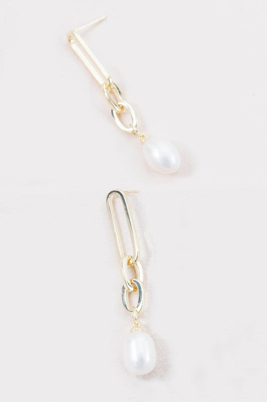 The Secured Pearl Drop Earrings showcase 14k gold plated chains with freshwater pearl pendants, artistically presented against a light background.