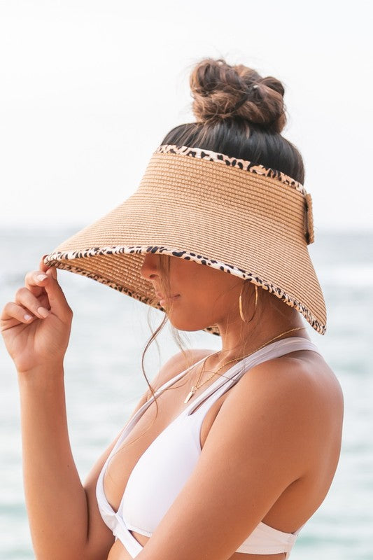 Woman holding her Leopard Foldable Bow Visor, looking out to the sea.