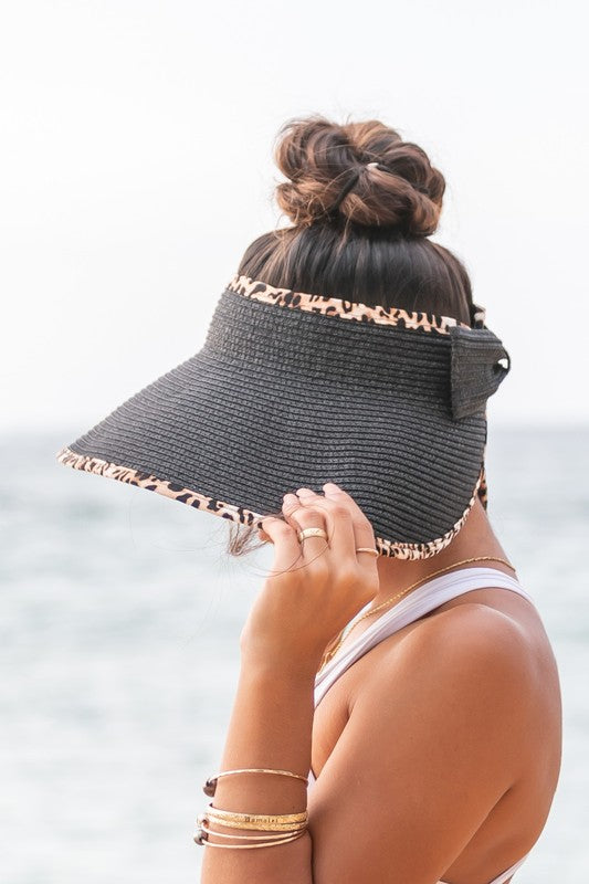 Woman holding her Leopard Foldable Bow Visor, looking out to the sea.