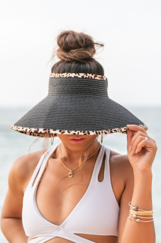 Woman holding her Leopard Foldable Bow Visor, looking out to the sea.