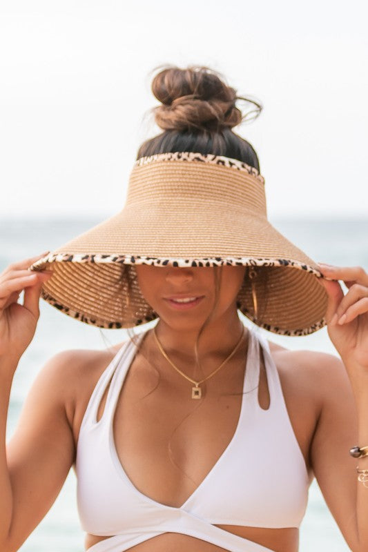 Woman holding her Leopard Foldable Bow Visor, looking out to the sea.