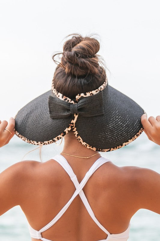 Woman holding her Leopard Foldable Bow Visor, looking out to the sea.