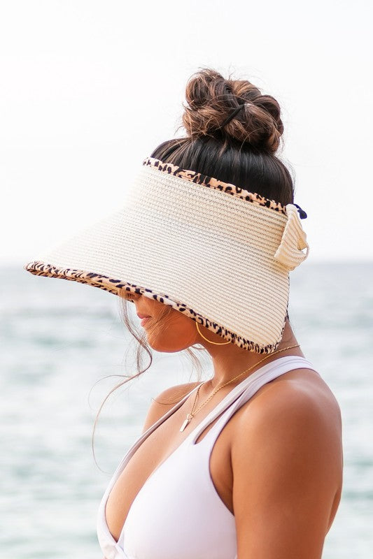 Woman holding her Leopard Foldable Bow Visor, looking out to the sea.