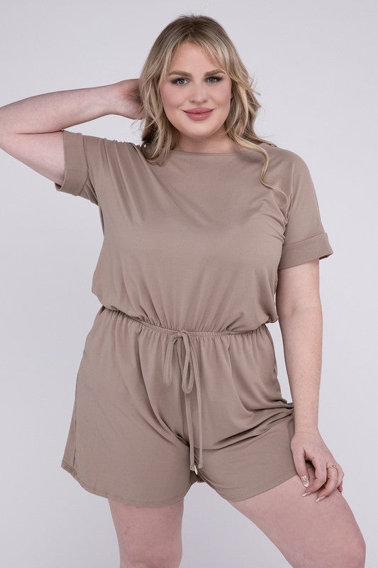 A person is wearing the Plus Brushed DTY Romper with Pockets in bright pink, smiling as they pose with one hand on their head and the other tucked into a pocket, all set against a gray background.