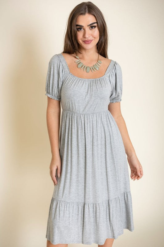 A woman in a Square Neck Puff Sleeve Boho Dress stands against a light background, smiling with her long hair down and wearing high heel sandals.