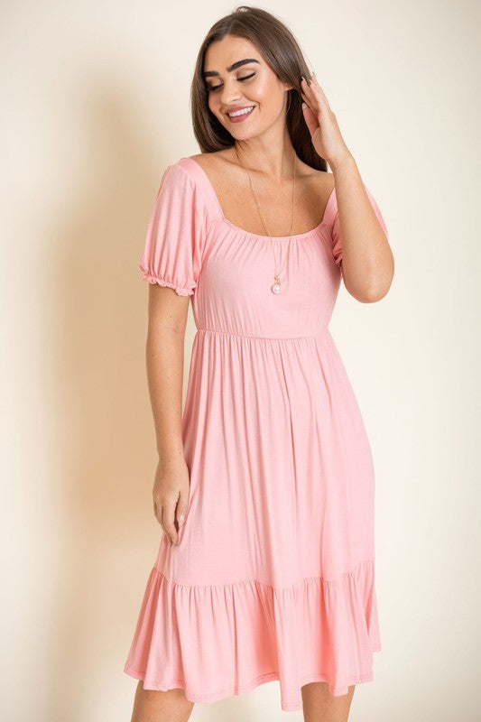 A woman in a Square Neck Puff Sleeve Boho Dress stands against a light background, smiling with her long hair down and wearing high heel sandals.