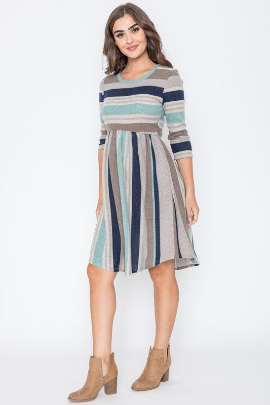 A woman is dressed in the Stripe Curved Hem Midi Dress, made from a polyester-spandex blend and showcasing three-quarter sleeves, standing against a plain white background. This dress, made in the United States, seamlessly blends style with comfort.