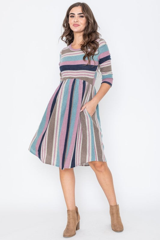 A woman is dressed in the Stripe Curved Hem Midi Dress, made from a polyester-spandex blend and showcasing three-quarter sleeves, standing against a plain white background. This dress, made in the United States, seamlessly blends style with comfort.