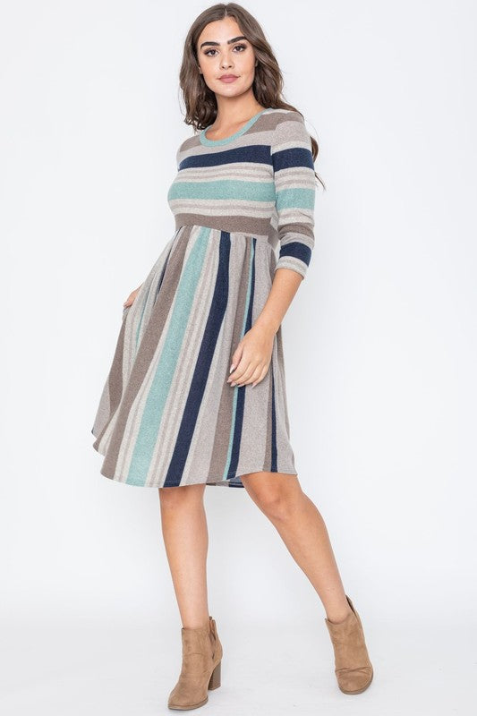 A woman is dressed in the Stripe Curved Hem Midi Dress, made from a polyester-spandex blend and showcasing three-quarter sleeves, standing against a plain white background. This dress, made in the United States, seamlessly blends style with comfort.