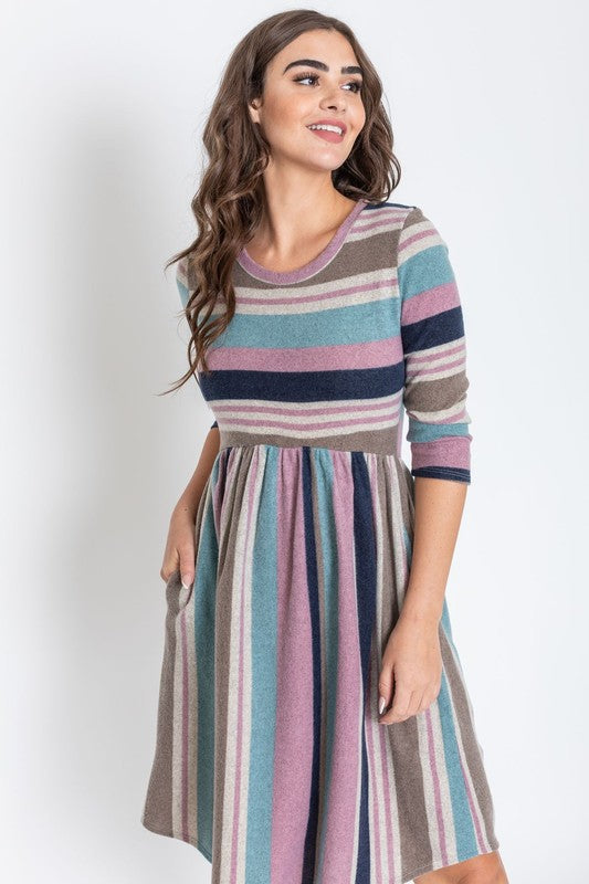 A woman is dressed in the Stripe Curved Hem Midi Dress, made from a polyester-spandex blend and showcasing three-quarter sleeves, standing against a plain white background. This dress, made in the United States, seamlessly blends style with comfort.