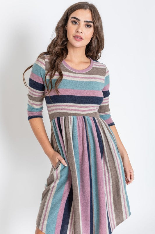 A woman is dressed in the Stripe Curved Hem Midi Dress, made from a polyester-spandex blend and showcasing three-quarter sleeves, standing against a plain white background. This dress, made in the United States, seamlessly blends style with comfort.