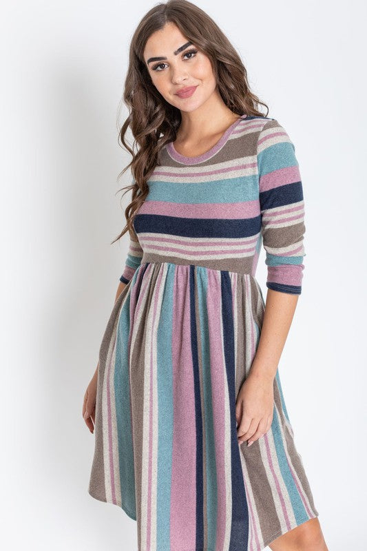 A woman is dressed in the Stripe Curved Hem Midi Dress, made from a polyester-spandex blend and showcasing three-quarter sleeves, standing against a plain white background. This dress, made in the United States, seamlessly blends style with comfort.