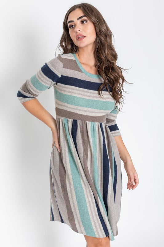 A woman is dressed in the Stripe Curved Hem Midi Dress, made from a polyester-spandex blend and showcasing three-quarter sleeves, standing against a plain white background. This dress, made in the United States, seamlessly blends style with comfort.