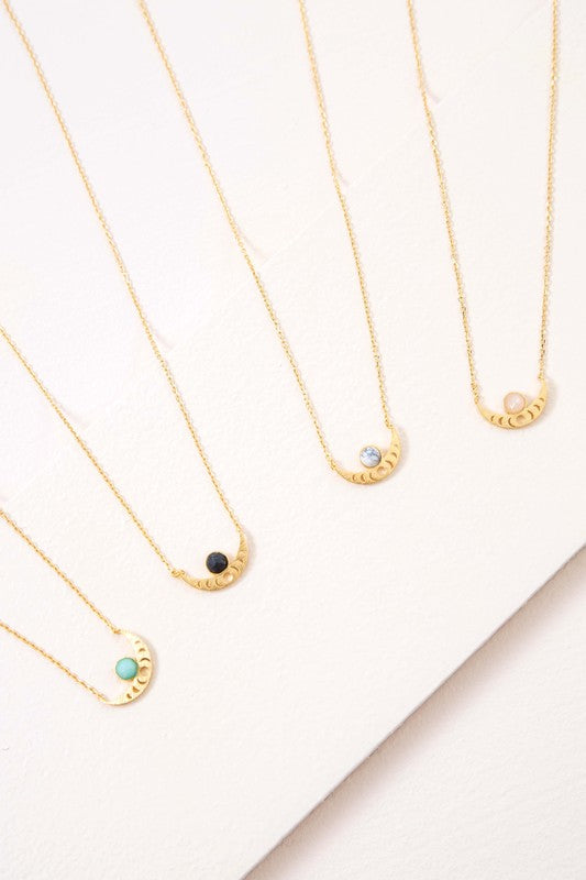 The Rumi Stone Necklace collection showcases five Bohemian-style stone and gold necklaces with crescent-shaped pendants, each adorned with a uniquely colored stone, beautifully displayed on a white background.