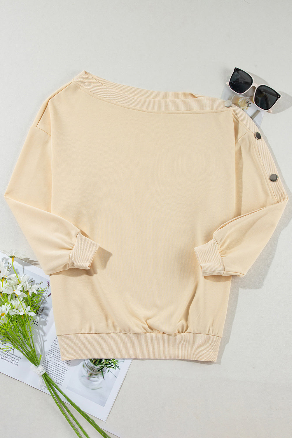 Woman with long wavy hair wearing the Beige Buttoned Sleeve Dropped Shoulder Sweatshirt, standing in a bright indoor setting.