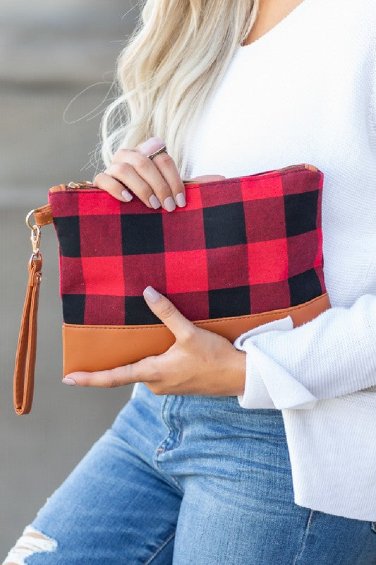 A person with long blonde hair holds the Buffalo Plaid Clutch, featuring a PU leather trim, while wearing blue jeans and a white sweater.