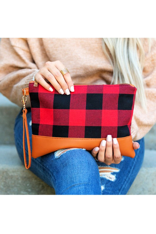 A person with long blonde hair holds the Buffalo Plaid Clutch, featuring a PU leather trim, while wearing blue jeans and a white sweater.