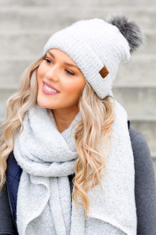 Woman wearing a CC Ultra Soft Fur Pom Beanie and a scarf, smiling at the camera.