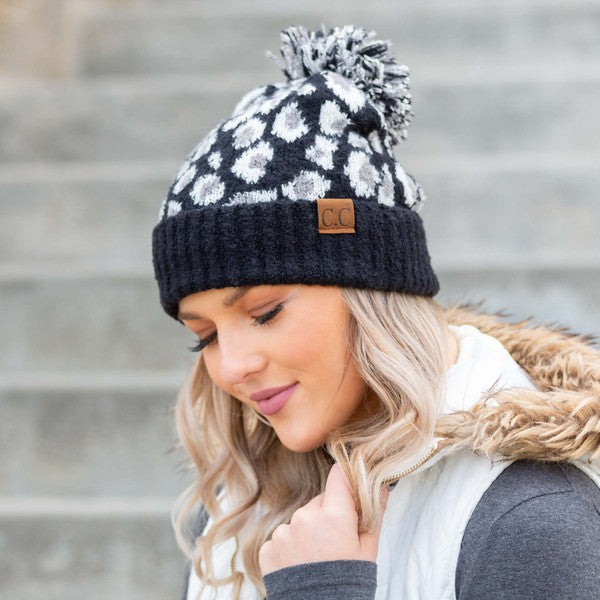 Woman smiling while wearing a CC Leopard Pom Beanie.