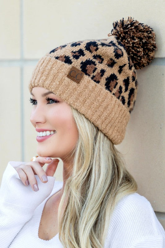 Woman smiling while wearing a CC Leopard Pom Beanie.