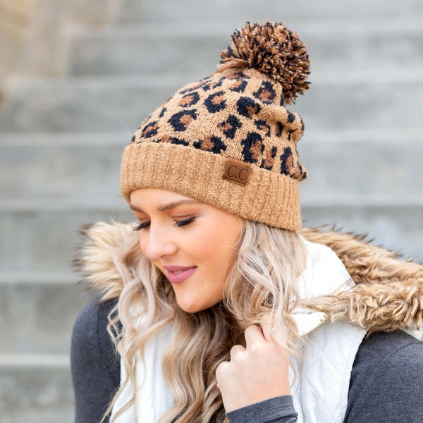 Woman smiling while wearing a CC Leopard Pom Beanie.