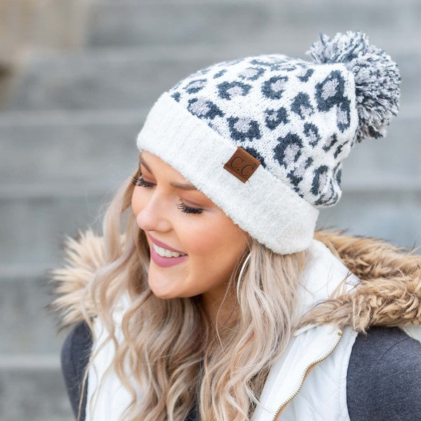 Woman smiling while wearing a CC Leopard Pom Beanie.