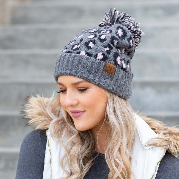 Woman smiling while wearing a CC Leopard Pom Beanie.
