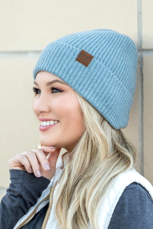 A smiling woman wearing a gray CC Fine Yarn Cuff Beanie boyfriend fit beanie with a brown leather logo patch.