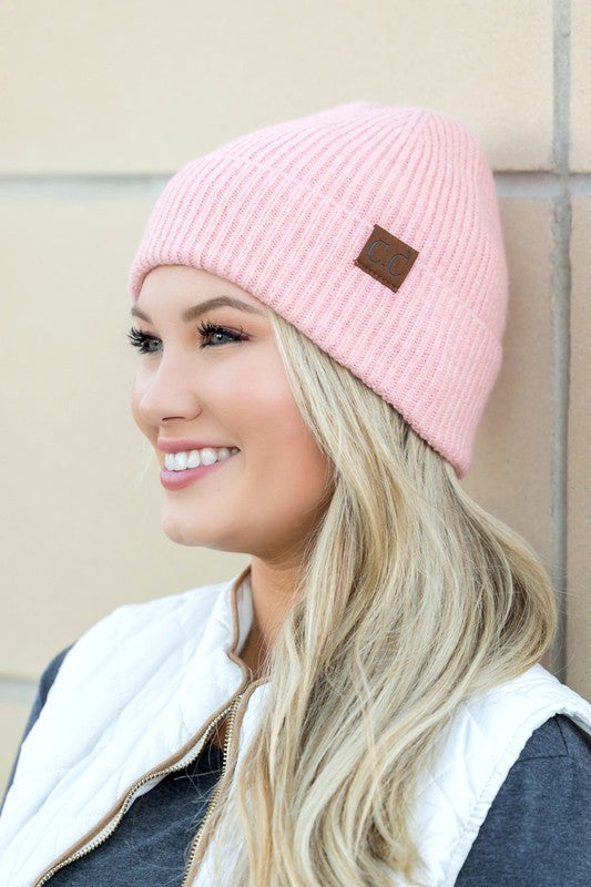 A smiling woman wearing a gray CC Fine Yarn Cuff Beanie boyfriend fit beanie with a brown leather logo patch.