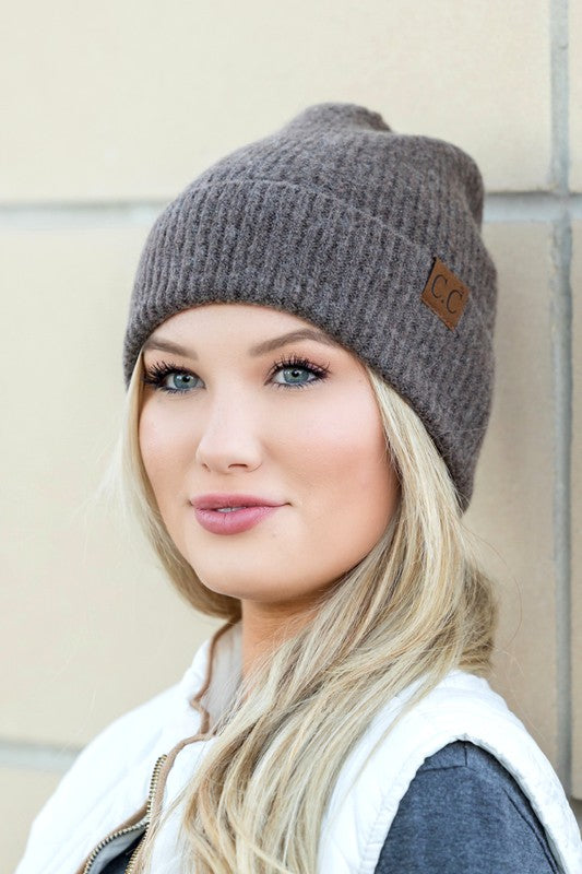 A smiling woman wearing a gray CC Fine Yarn Cuff Beanie boyfriend fit beanie with a brown leather logo patch.