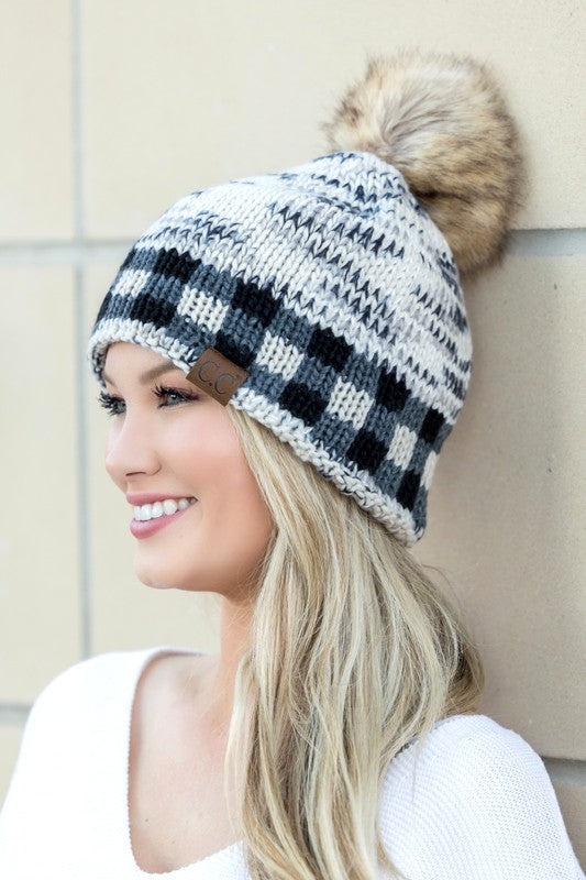 Woman smiling and wearing a CC Buffalo Pom Beanie with a houndstooth pattern.