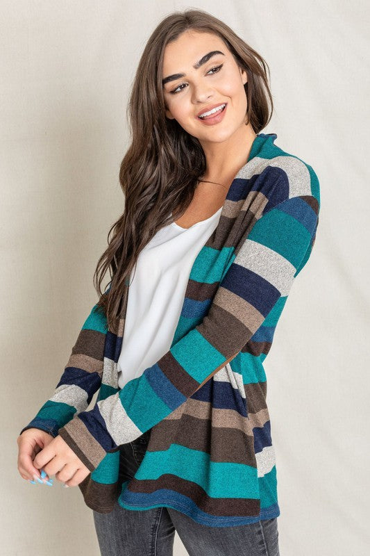 Dressed in a vibrant Stripe Elbow Patch Cardigan composed of soft spandex and polyester, paired with a white top and jeans, an individual stands against a light background.