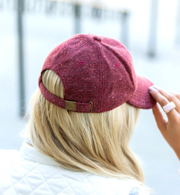 Woman smiling and wearing a Fall Tweed Ball Cap with an adjustable clasp and hoop earrings.
