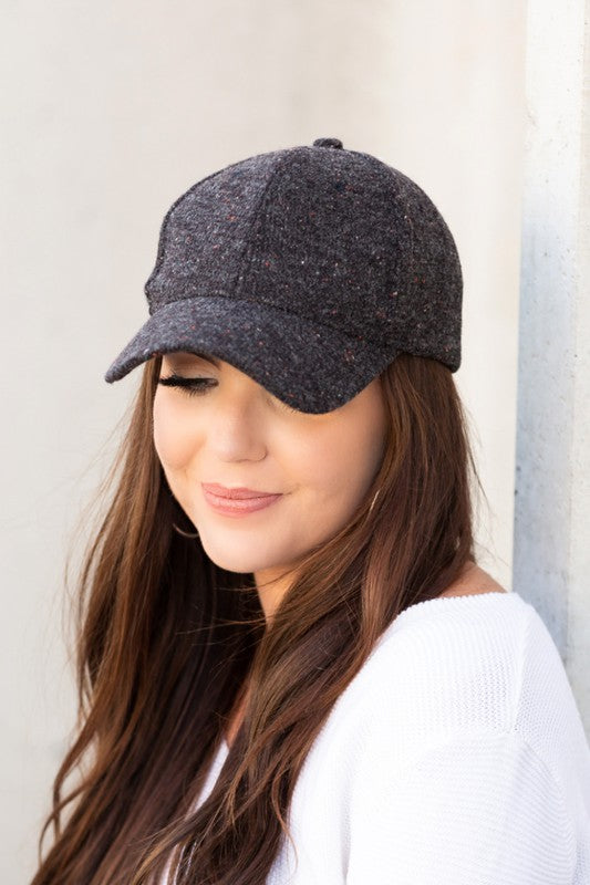 Woman smiling and wearing a Fall Tweed Ball Cap with an adjustable clasp and hoop earrings.